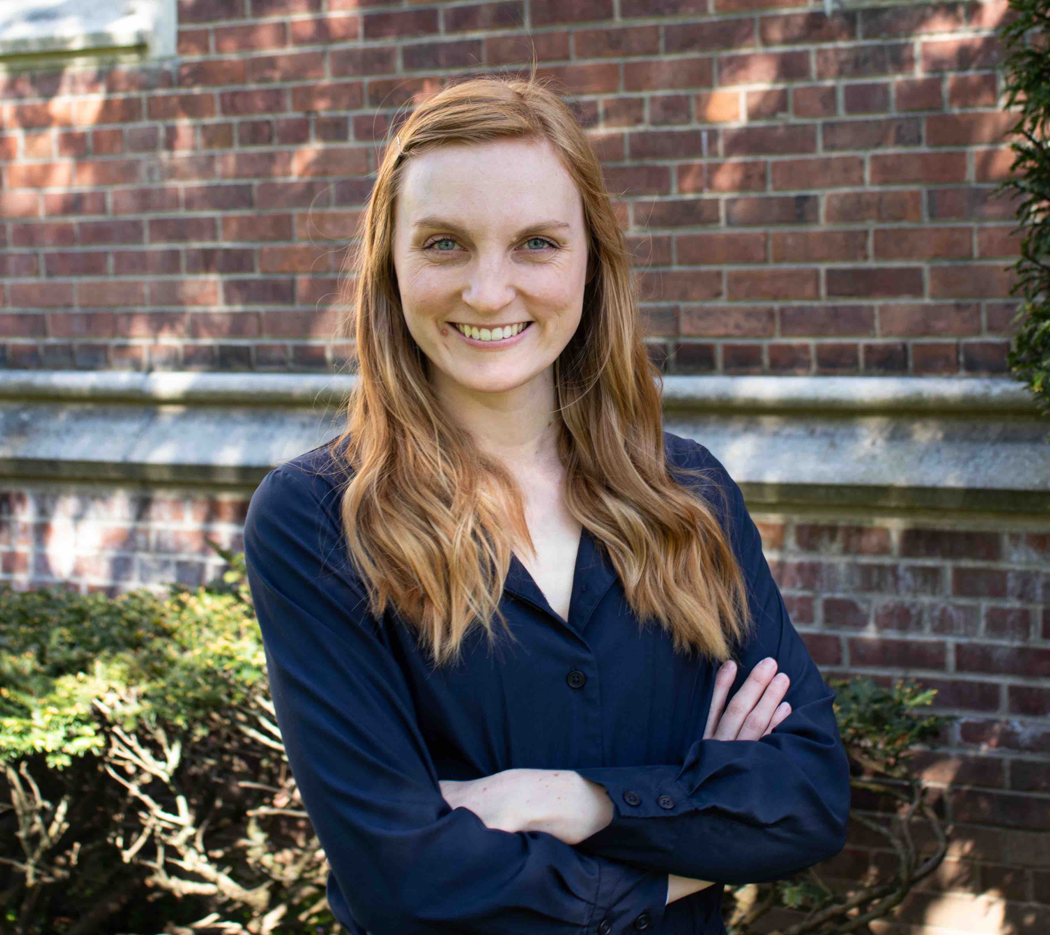 Headshot of Hannah Barber with a brick background